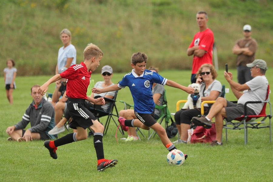 Youth soccer player competing while parents watch from the sideline